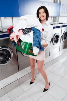 Woman carrying a laundry basket in a laundromat