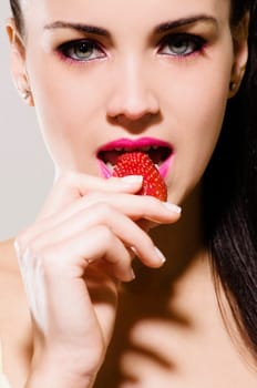 Portrait of a young woman eating a strawberry