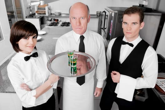 Two waiters and a waitress standing in the kitchen