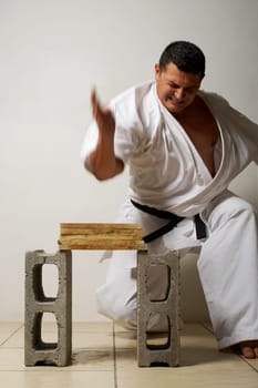 Mid adult man breaking a stack of woods with his hand