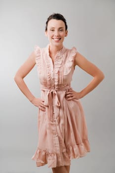 Portrait of a young woman standing with arms akimbo and smiling