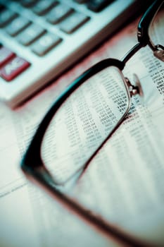 Eyeglasses and a calculator on a financial newspaper