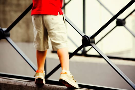 Low section view of a boy leaning against a railing