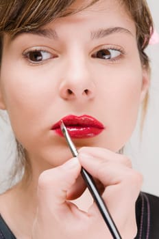 Close_up of a young woman applying lipstick