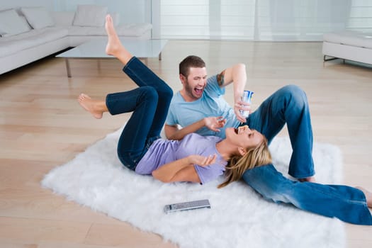 Young man feeding whipped cream from a bottle to a mid adult woman