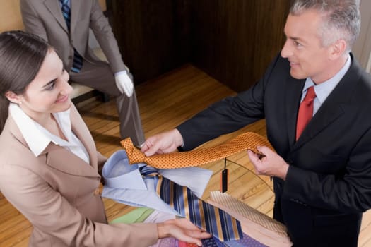 Saleswoman assisting a businessman in a clothing store