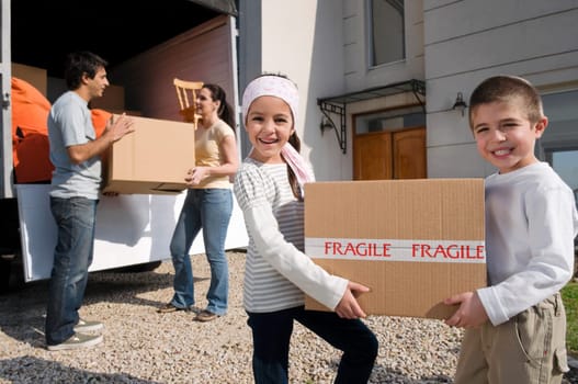 Couple with their children unloading boxes from a pick_up truck
