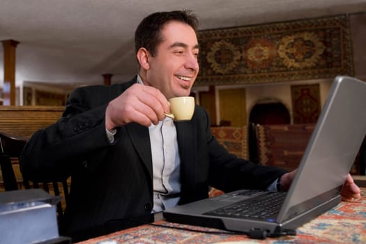Businessman using a laptop in a restaurant and smiling