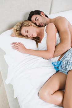 High angle view of a young man and a mid adult woman lying on the bed