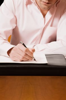 Businessman writing on a sheet of paper with a pen