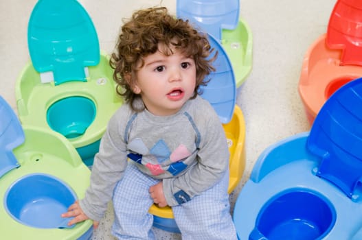 Baby boy sitting on a pot seat in a supermarket