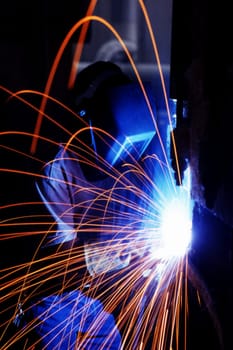 Welder working on a piece of metal with sparks flying