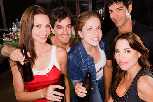 Portrait of five friends smiling at a bar counter