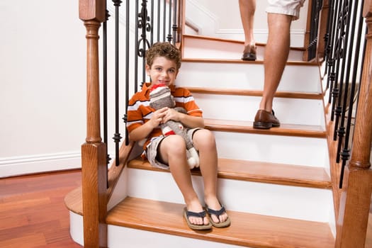 Boy sitting on a staircase and holding a toy