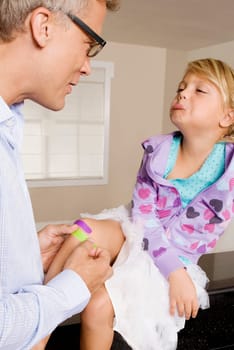 Man applying bandage on his daughterŽs knee