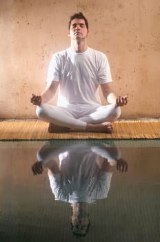 Mid adult man practicing yoga at the poolside