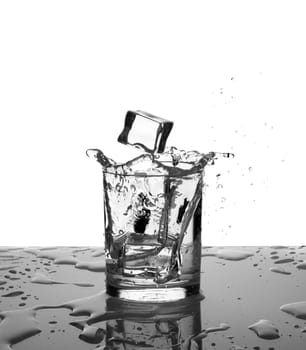 Splashing water. Glass with water or alcohol with splashes from falling ice cubes isolated on white background