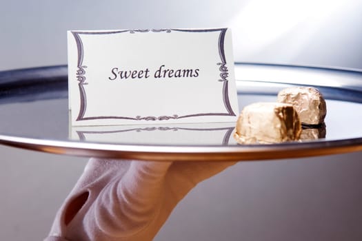 Close_up of a waiterŽs hand carrying a plate with sweet dreams note and chocolates