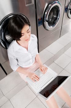 Woman using a laptop in a laundromat
