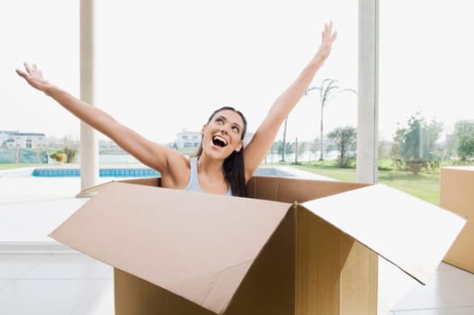 Young woman sitting in a cardboard box and laughing