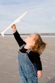 Baby girl playing with a model airplane on the beach
