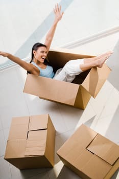 High angle view of a young woman laughing in a cardboard box