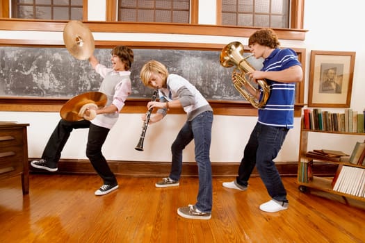 Three students playing musical instruments in a classroom