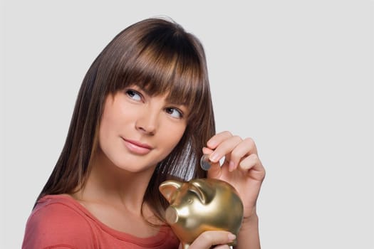 Close_up of a young woman inserting a coin into a piggy bank