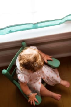 High angle view of a baby girl sitting in an armchair