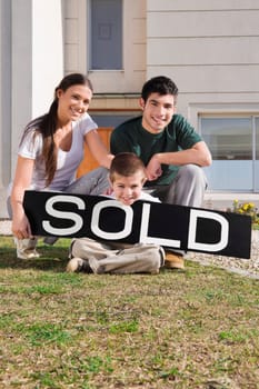 Young couple and their son sitting with a sold information board