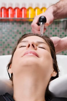 Young woman getting hair rinsed at salon