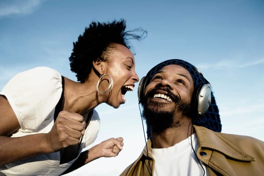Mid adult man listening to music and a young woman shouting in front of him