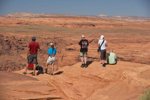 Tourists standing on an arid landscape, Horseshoe Bend, Page, Arizona, USA