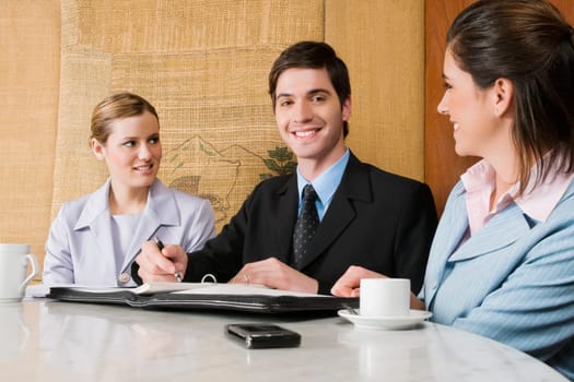 Two businesswomen and a businessman discussing in a cafe
