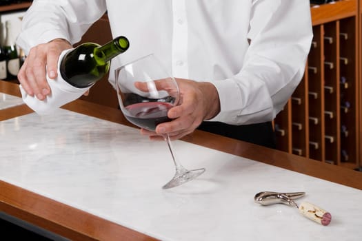 Waiter pouring wine into a glass