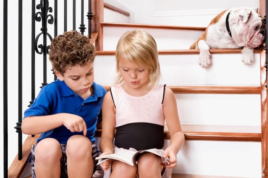 Boy and a girl sitting on a staircase and reading a book