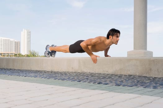 Young man doing push ups on the ledge