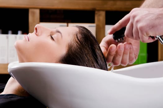 Young woman getting hair rinsed at salon