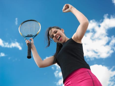Low angle view of a female tennis player holding a tennis racket with her hands raised