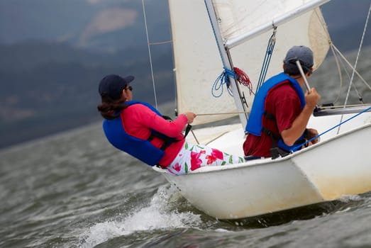Side profile of two people participating in a sailboat race