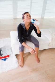 Young woman sitting on the bed and drinking water