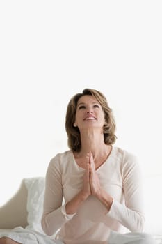 Woman sitting in a prayer position on the bed