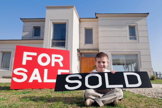 Portrait of a boy holding a sold signboard and smiling