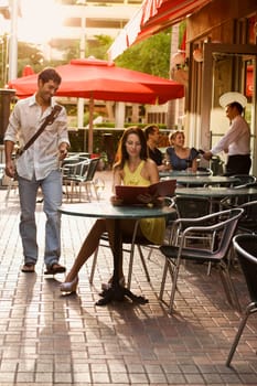 Young woman looking at a menu with a young woman smiling at a sidewalk cafe