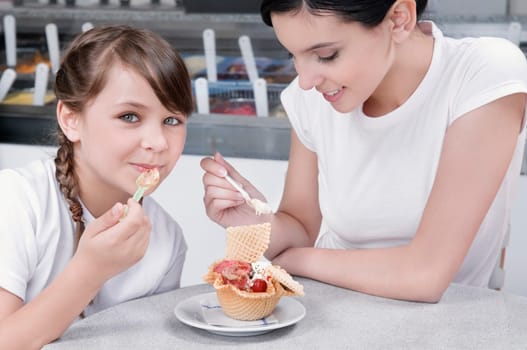 Girl and a teenage girl eating ice cream in an ice cream parlor