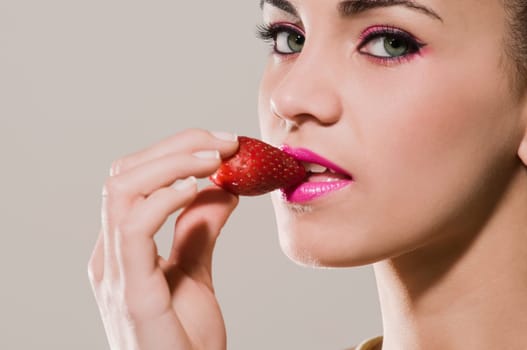 Portrait of a young woman eating a strawberry