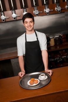 Cafe owner standing at a cafe counter and smiling