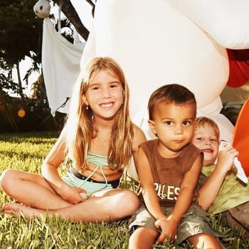 Portrait of three children sitting in the lawn and smiling