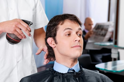 Barber spraying water on a manŽs hair