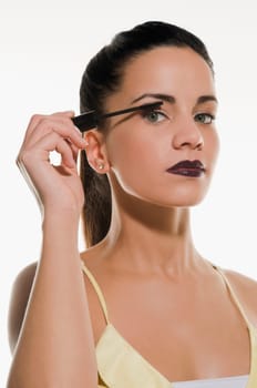 Portrait of a young woman applying mascara